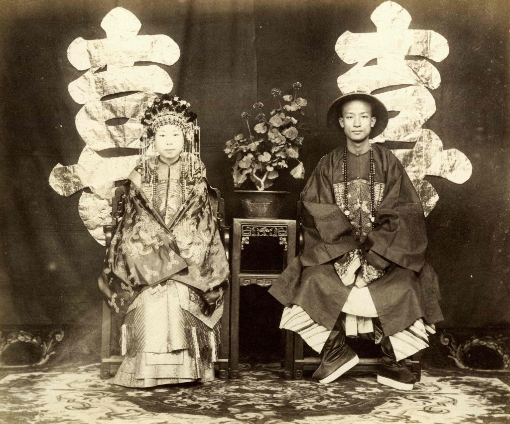 A portrait of a bride and groom in front of a studio screen with chinese lettering.